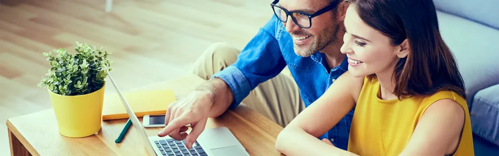Couple reviewing information on a laptop at home.

