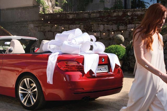 BMW Service Technician in service bay inspecting a BMW on a lift