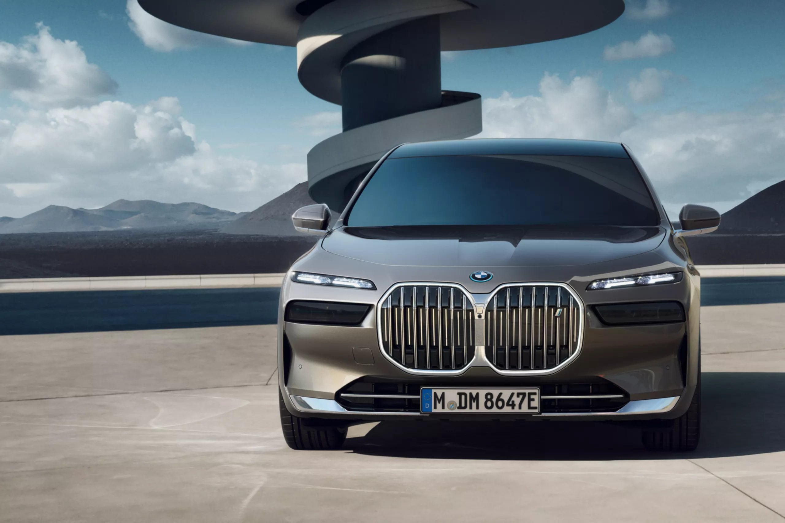 BMW sedan parked in a modern architectural setting with a mountain backdrop.